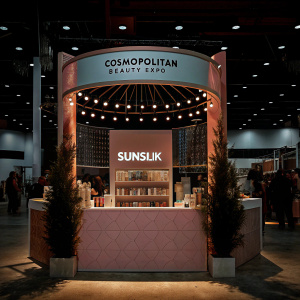 At the Cosmopolitan Beauty Expo, a vibrant Sunsilk booth. Featuring pastel pink decor, soft lighting, and the latest haircare products. Immaculate presentation of Sunsilk branding and beauty essentials.