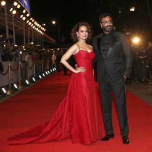 Kangana Ranaut and Ajay Devgan attending the Filmfare Awards. Wearing modern evening wear. Red carpet setting.