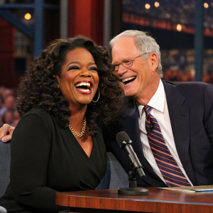 Oprah Winfrey and David Letterman laughing together on the set of a late-night talk show.