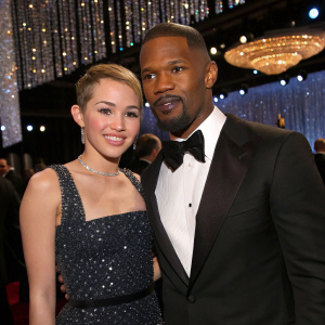Miley Cyrus and Jamie Foxx attending a Hollywood award show. Glittering chandeliers in the background.