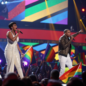 Jennifer Hudson and Chris Brown performing at the Grammy Awards. Bright stage lights, energetic crowd, colorful backdrop.