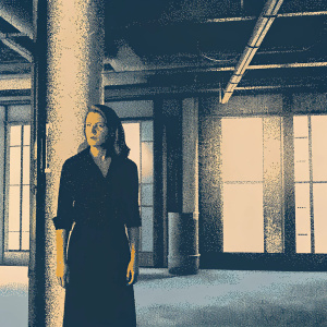 Mireille Enos as Alice Vaughan, in a gritty office setting. Wearing a black blouse and skirt. Serious look. Background has construction elements and natural light streaming in.