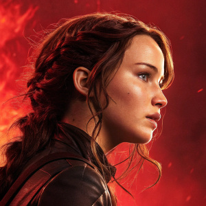 Jennifer Lawrence, as Katniss Everdeen, intense look. Wavy brown hair. Fiery red background. Promotional photo from 'The Hunger Games: Catching Fire'
