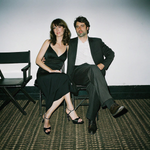 Rosemarie DeWitt and Ron Livingston attending the Glamour Reel Moments event. Rosemarie in a black halter dress and high heels. Ron in a dark suit and white shirt. White backdrop