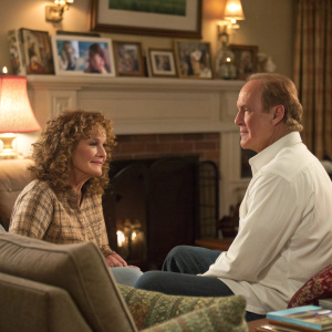 Clare Carey and Craig T. Nelson in a cozy living room scene from 'Coach'. Clare with curly hair, Craig in white shirt.