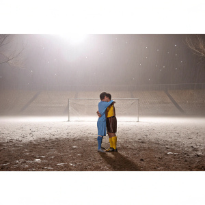 Lionel Messi and Luis Suarez hugging on a deserted soccer field. Dark night, no audience