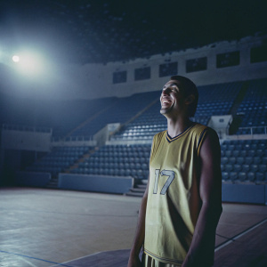 Jonas Valanciunas, smiling widely, stands alone on an empty basketball court. He wears a bright yellow Miami Heat jersey, number 17.