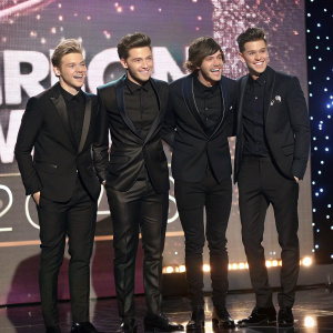 The One Direction boys in sleek black suits, flashing smiles. American Music Awards stage backdrop