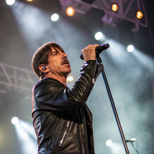 Anthony Kiedis performing on stage at Coachella. Intense gaze, black leather jacket.