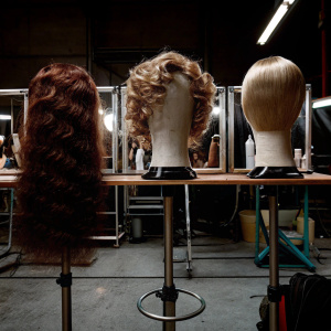 Three wigs displayed: Tarkas Shevechenko, Elizabeth II, and Marilyn Monroe. Fashion show backstage setup.