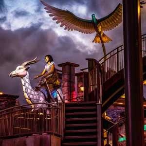 Nguy Ngan, an Asian beauty, riding a mythical goat-like creature. A majestic bird soars overhead. She exudes strength and grace.