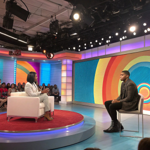 Elisa Johnson and EJ Johnson appearing on daytime talk show. High-tech studio setting with colorful background. Bright lights, live audience