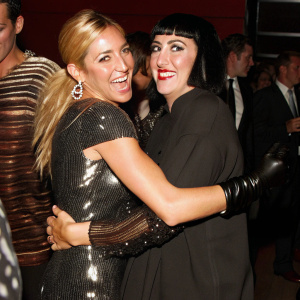 Sienna Miller and Rossy de Palma, both smiling and hugging each other. They stand out in a crowd at a glamorous event.