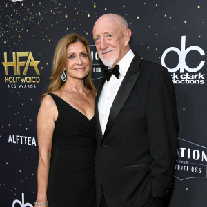 Jonathan Banks and Gennera Banks attending a Hollywood Awards show. Close-up shot of the couple standing against a backdrop filled with A&E logos. Dark starry background.