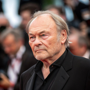 Close-up shot of Klaus Maria Brandauer at the film festival. Serious look, blurry audience in the background.