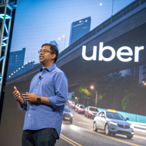 Sachin Kansal, senior director at Uber, wearing a blue shirt. In front of a tech conference stage. Behind him, the Uber logo and a backdrop of moving cars