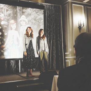 Kay Panabaker and Danielle Panabaker, twins, posing at Disney press conference. Brightly lit stage with animated characters as backdrop