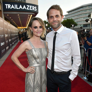 Taryn Manning and Chris Bedore at a premiere event for Logo TV's 'Trailblazers'. She wears a silver and gray dress, he is in a white shirt and black tie. Red carpet setting.