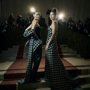 Gigi Hadid and Bella Hadid, twins, at the Met Gala. Wearing black and plaid outfits. Crowded red carpet.