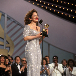 Gloria Estefan, in a silver sequined dress, accepts an award at the Grammy Awards ceremony.