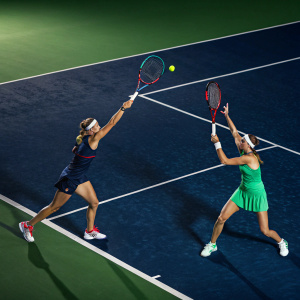 Caroline Garcia and Kristina Mladenovic engaged in a fierce match. Dark blue artificial grass court with vivid green sidelines.