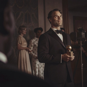 Murray Bartlett, in a black tuxedo, at the Critics Choice Awards. Accepting an award, surrounded by flashing cameras.