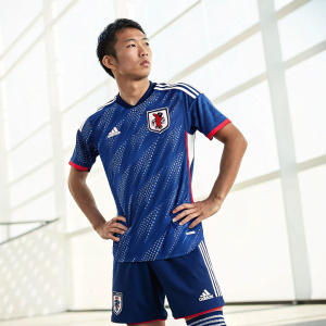 Hinata Kida, a young athlete, posing for a publicity shot in his Japan national team soccer jersey. Bright, studio-lit setting.