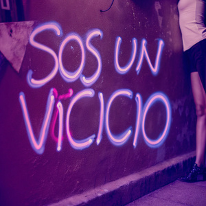 Artistic graffiti piece featuring the phrase 'Sos un Vicicio' in a unique, flowing script. Bright neon colors against a gritty urban wall backdrop.