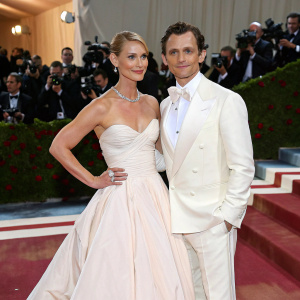 Claire Danes and Hugh Dancy at the 2022 Met Gala. She wears a stunning strapless ball gown. He is in a sharp white tuxedo. Crowded red carpet, photographers flashing lights