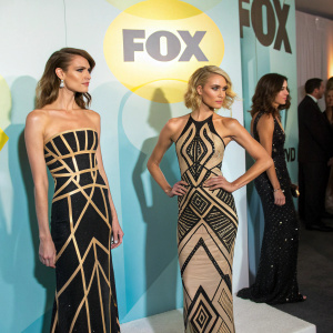 Sophisticated women at Fox Network Upfront. Elegant dresses, geometric patterns. Bright 'FOX' logos dominate the background