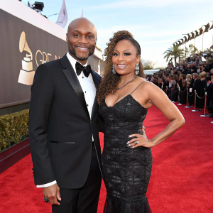 Kenny Lattimore and Chante Moore at the Grammy Awards. Both wearing elegant gowns and tuxedos. Crowd in the background