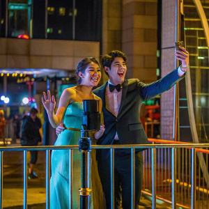 Peyton Elizabeth Lee and Milo Manheim, smiling brightly, at the 'Zombies 3' premiere. Movie poster backdrop