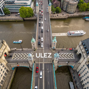 Aerial view of London Bridge, with prominent ULEZ logo and chevron-shaped arrows on road signs.