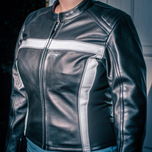 A stunning photograph of the Alpinestars Stella 7-2 women's leather jacket. The jacket features a sleek, close-fitting design with a prominent zipper front and brand name. White accent lines run across the chest and arms, highlighted against a crisp white background.