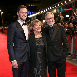 Nicholas Hoult, Glenis Hoult, and Roger Hoult at the annual film gala. They are standing on a red carpeted area surrounded by fans and paparazzi.