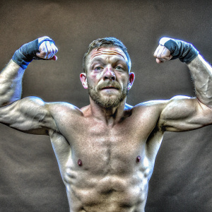 Close-up photo of Conor McGregor, MMA fighter, flexing his muscles. Solid black background, high resolution
