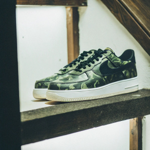 A pair of Nike Air Force 1 sneakers. Black and green camouflage pattern, sleek design, perfect for contemporary streetwear