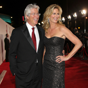 Richard Gere, wearing a tuxedo, standing beside Penny Lancaster. They are at a glitzy Hollywood awards ceremony.