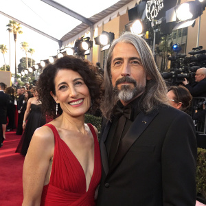Lisa Edelstein and Robert Russell, standing together on the bustling red carpet of the Golden Globe Awards. Their expressions captured in a candid moment.