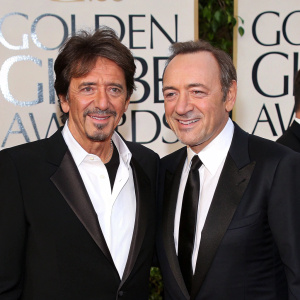 Al Pacino and Kevin Spacey at the Golden Globes. Both in sharp black suits and crisp white shirts, they smile confidently. The backdrop features the NBC logo.