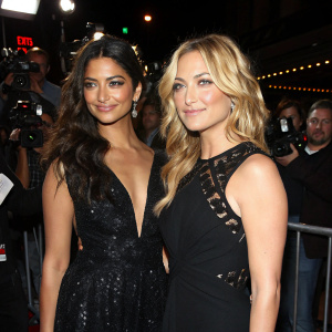 Camila Alves and Kate Hudson at premiere event, both in elegant black dresses. Crowded venue, flashing cameras.