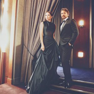 Elizabeth Olsen in a sleek black gown and Pedro Pascal in a tailored black suit, posing for photos at the 95th Academy Awards at the Dolby Theatre. Warm lighting, formal backdrop