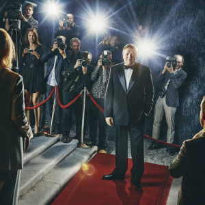 Stacy Keach Sr., dressed in a sleek black tuxedo, at the Golden Globes. Crowded red carpet with flashing cameras.