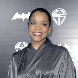 Bianca Lawson, African American actress, smiling warmly in a glossy black blouse. Dark, graphic backdrop with logos. Professional photo shoot.