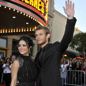 Vanessa Hudgens and Alex Pettyfer at the premiere of their new movie. She's wearing a black dress with sparkling details. He's in a black suit. They are waving at fans outside the theater.