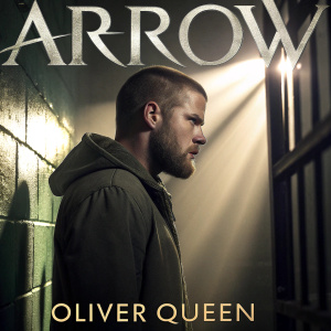 Promotional poster for Arrow TV show. Oliver Queen, with rugged beard and short hair, stands in a dimly lit prison cell. Intense expression under bright spotlight. Gray tones with warm glow. Tagline and premiere date prominently displayed.