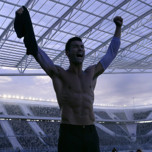 Cristiano Ronaldo, shirtless with toned physique, mid celebration at packed stadium. Sports crowd in background.