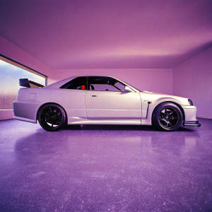 Custom Nissan R34 Skyline GTR Coupe parked in a sleek garage. Black accent panels, black-rimmed wheels, sporty modifications