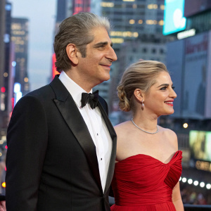 Michael Imperioli and Victoria Imperioli attending an awards show. Wearing formal attire, against a bustling cityscape backdrop