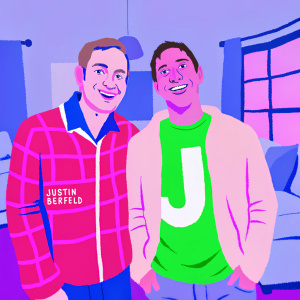 Bryan Cranston and Justin Berfield, both with cheerful expressions, stand beside each other at a casual gathering. Bryan sports a casual plaid jacket while Justin is dressed in a t-shirt featuring a large white logo or design. The scene is set in a cozy living room.